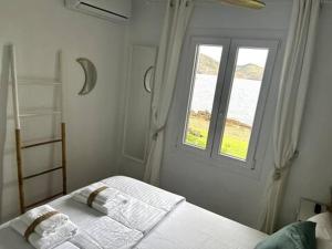 a white bedroom with a bed with a window at Miravent Terraza y Jardin Frente al mar Menorca in Fornells