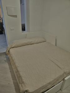 a bed in a white room with a tan comforter at Ermi Apartment Temù in Temù