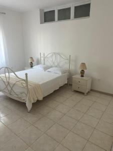 a bedroom with a white bed and two lamps on a table at Appartement avec Vue sur Mer à Praia, Wi-Fi, Navette Aéroport in Praia