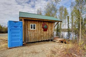 a wooden cabin with a green roof and a blue door at Bass Farm Twin Lakes Couples Dry Cabin in Wasilla