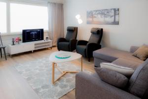 a living room with a couch and chairs and a tv at Apartments Rovakatu C19 in Rovaniemi