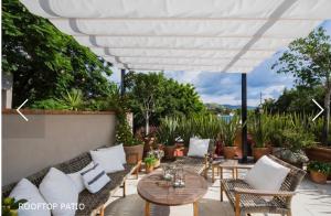 サンミゲル・デ・アジェンデにあるCasa Zenaida in the heart of San Miguel Allendeの白い傘の下に籐の椅子とテーブルが置かれたパティオ
