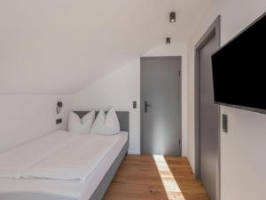 a white bedroom with a bed and a flat screen tv at Leni Top 6 in Dienten am Hochkönig