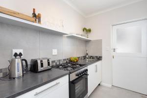 a kitchen with a stove top oven next to a refrigerator at Camps Bay private room and bathroom in Cape Town