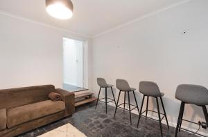 a living room with a couch and four stools at Camps Bay private room and bathroom in Cape Town