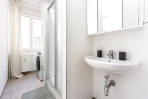 Un baño blanco con lavabo y espejo. en Sleep better here! central oasis of well-being, en Graz