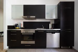 cocina con armarios blancos y negros y lavavajillas en Sleep better here! central oasis of well-being, en Graz