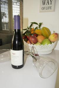 a bottle of wine next to a bowl of fruit at צימר ברחובות - Israeli Home in Rechovot