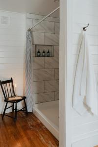 ein Badezimmer mit einer Dusche und einem Stuhl neben einer Badewanne in der Unterkunft Book Village Inn - Twain Room Queen Bed in Hobart