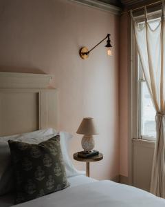 a bedroom with a bed with a lamp and a window at Book Village Inn - Fitzgerald Room King Bed in Hobart