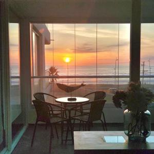 a table and chairs on a balcony with a view of the ocean at Descansa frente al mar y disfruta todos los días del año en Neohaus in La Serena