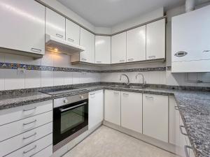 Una cocina blanca con gabinetes blancos y un fregadero. en Apartment in Calella by the Beach, en Calella