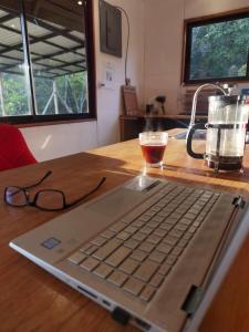 a laptop computer sitting on a wooden table with a drink at Casa Roble Cabaña romántica en la montaña de Costa Rica in San Cristóbal Sur