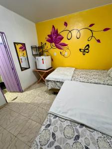 a bedroom with two beds and a yellow wall at Pousada Rosa de Saron - Algodoal in Algodoal
