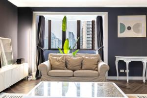 ein Wohnzimmer mit einer Couch und einem Fenster in der Unterkunft Omni Nuvél 4 Sukhumvit Branded Suites in Bangkok
