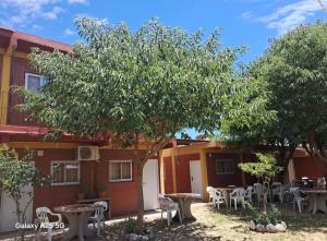 a building with tables and chairs and a tree at Hospedaje Pringles in Santa Rosa del Conlara