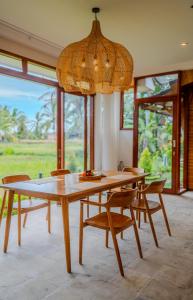a dining room table with chairs and a chandelier at Prana Eco Wooden Villa in Ubud
