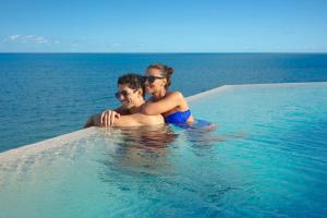un uomo e una donna seduti in una piscina nell'oceano di Dreams Sapphire Resort & Spa a Puerto Morelos