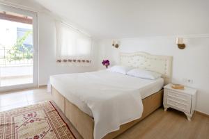 a white bedroom with a large bed and a window at Kaya Apart Datca in Datca