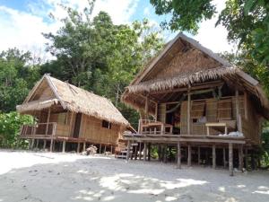two houses with thatched roofs on a beach at Batanta Panorama Guest' Hause in Pulau Batanta +38 photos