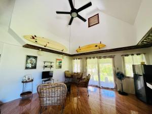 a living room with a ceiling fan and surfboards on the wall at Villa Barnes Siargao in General Luna