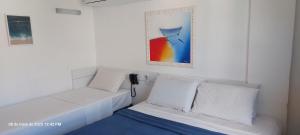 a white bed with white pillows and a picture on the wall at Flat Easy Sunset in João Pessoa