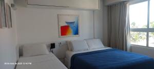 a white bedroom with a bed and a window at Flat Easy Sunset in João Pessoa