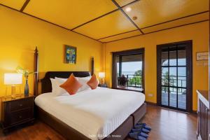 a bedroom with a large bed with yellow walls at Baan Krating Khao Lak Resort - SHA plus in Khao Lak