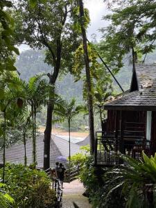 a person with an umbrella standing in front of a house at Baan Krating Khao Lak Resort - SHA plus in Khao Lak