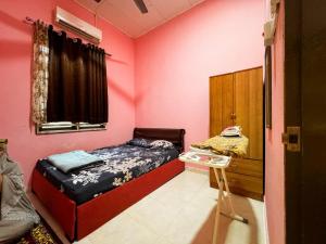 a bedroom with pink walls and a bed and a table at Izzah homestay pcb in Kota Bharu