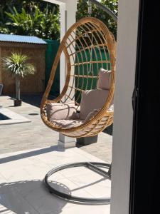 a wicker chair on a patio with a hose at Villa Sheba in Lamentin