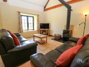 ein Wohnzimmer mit einem Ledersofa und einem Holzofen in der Unterkunft Keepers Cottage in Blandford Forum