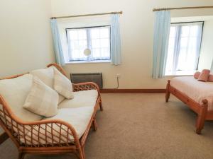 ein Zimmer mit einer Couch und einem Bett und zwei Fenstern in der Unterkunft Keepers Cottage in Blandford Forum