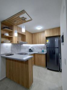 a kitchen with wooden cabinets and a black refrigerator at Moderno apto cómodo bien ubicado in Floridablanca
