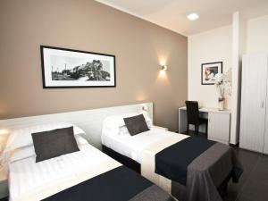 ナポリにあるステラ ホテル ザ ビジネストのベッド2台とデスクが備わるホテルルームです。