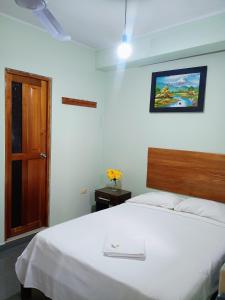 a bedroom with a white bed with a wooden headboard at Hospedaje Bello Horizonte in Tarapoto