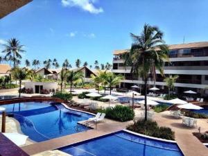 a resort with a pool and a building and palm trees at Malawi Resort Essence in Porto De Galinhas