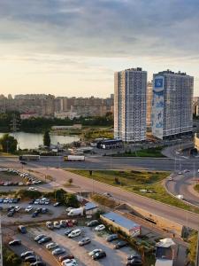 a parking lot with cars in a city with tall buildings at Уютная квартира метро Харьковская 3 мин, Паспорт-Сервис, Аэропорт Борисполь in Kyiv