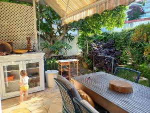 a child standing on a patio with a table at Garden & Terrace Apartment in Noumea