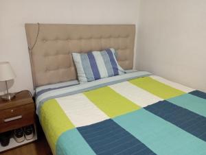 una camera da letto con un letto con una coperta colorata a righe di Alojamiento cerca a Metro Moneda a El Cerrillo