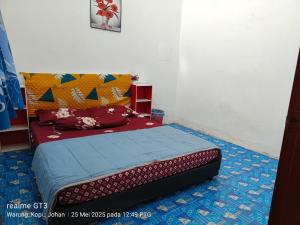 a bedroom with a bed with a blue and red blanket at Kuala Rompin Town Homestay in Kuala Rompin