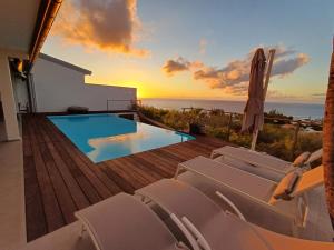 une terrasse avec des chaises et une piscine avec le coucher du soleil dans l'établissement Villa Antelisa piscine et vue océan, à Saint-Paul