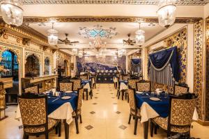 a restaurant with blue tables and chairs and a chandelier at Umaid Bhawan - A Heritage Style Boutique Hotel in Jaipur