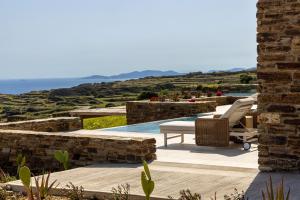 a patio with a pool and chairs and the ocean at Soborgo Exquisite Villas in Tinos Town