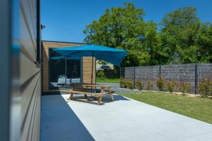 a picnic table with an umbrella on a patio at La Tiny L Loches, proche Zoo de Beauval in Loches +6 photos