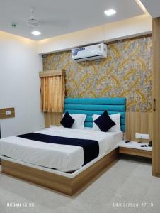 a bedroom with a bed with a blue headboard at Hotel Bhavya Palace in Anand