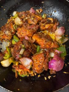a frying pan filled with meat and vegetables at Sherpa Homestay in Siliguri