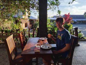 a man sitting at a table with a plate of food at Fetung Bayan Homestay in Senaru +9 photos