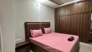 a small bedroom with a pink bed and wooden cabinets at LivingStone Sky Hills Apartment Kasauli in Kasauli
