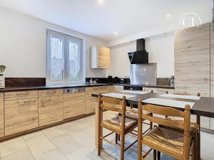 a kitchen with wooden cabinets and a table with chairs at Au murmure de l eau in Ebersheim
